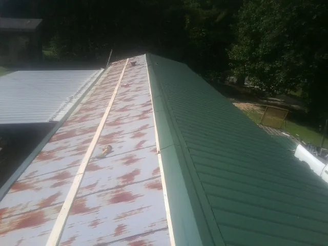 Old rusted panels beside newly installed green metal roofing — Wind Damage Roof Repair by Roofing Brothers in Parkville