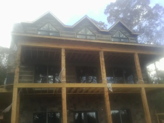 Dormers and porch framing on a large log home under construction — Roof Coating work by our crew in Parkville