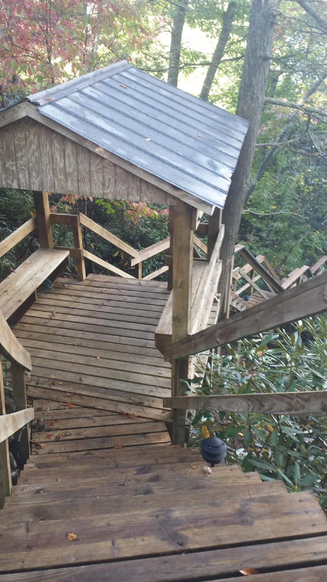 Metal roofed shelter over wooden steps on a wooded walkway — Skylight Repair & Installation work by our crew in Parkville
